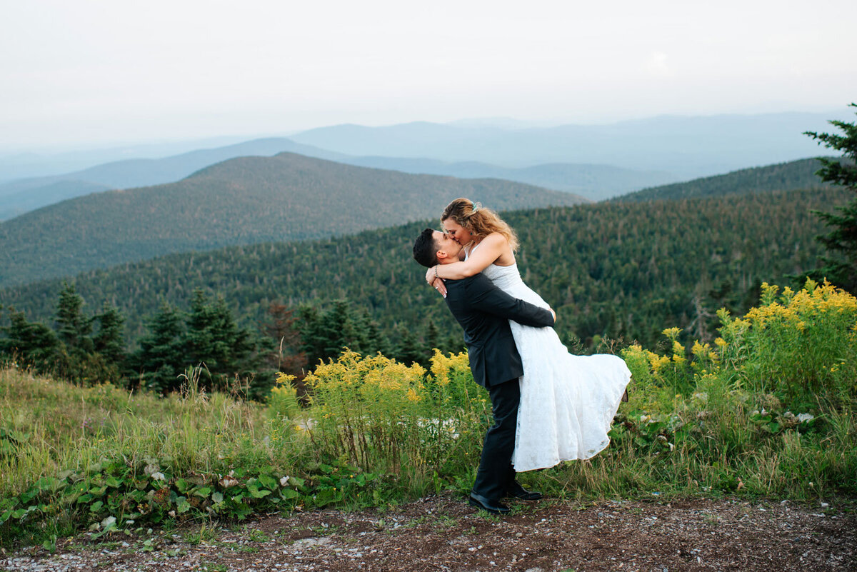 bride and groom kiss on mountain top at killington resort wedding
