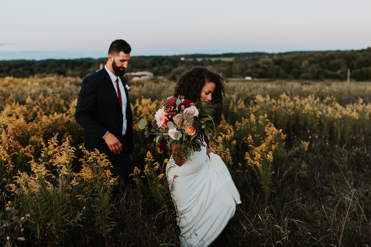 color image of bride and groom walking in a goldenrod field at Willowbrook wedding venue in PIttsburgh