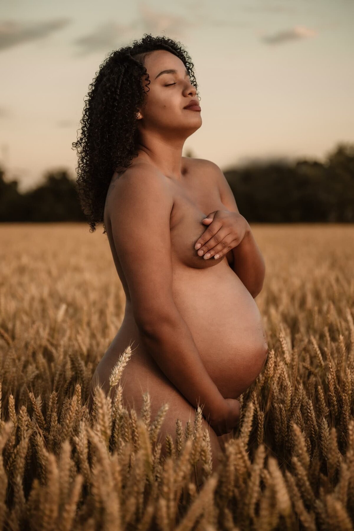 Zwangere vrouw in veld tijdens golden hour zwangerschapsshoot