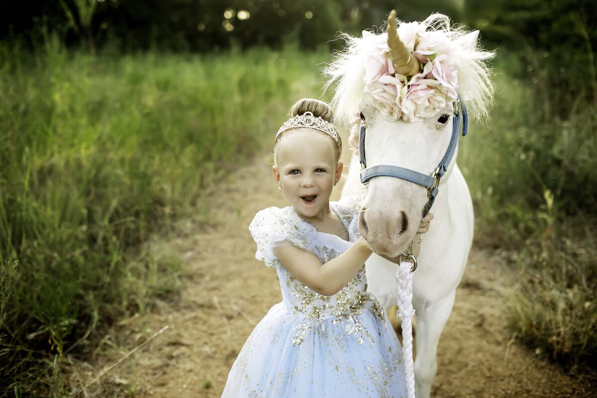 A fairytale princess birthday shoot featuring a majestic unicorn, with the birthday girl dressed in a dreamy gown, surrounded by magical elements