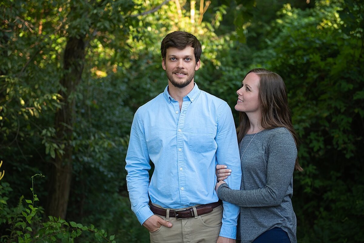 Bride-to-be looking at her fiancé during their engagement session in a wooded area of Pittsburgh, PA