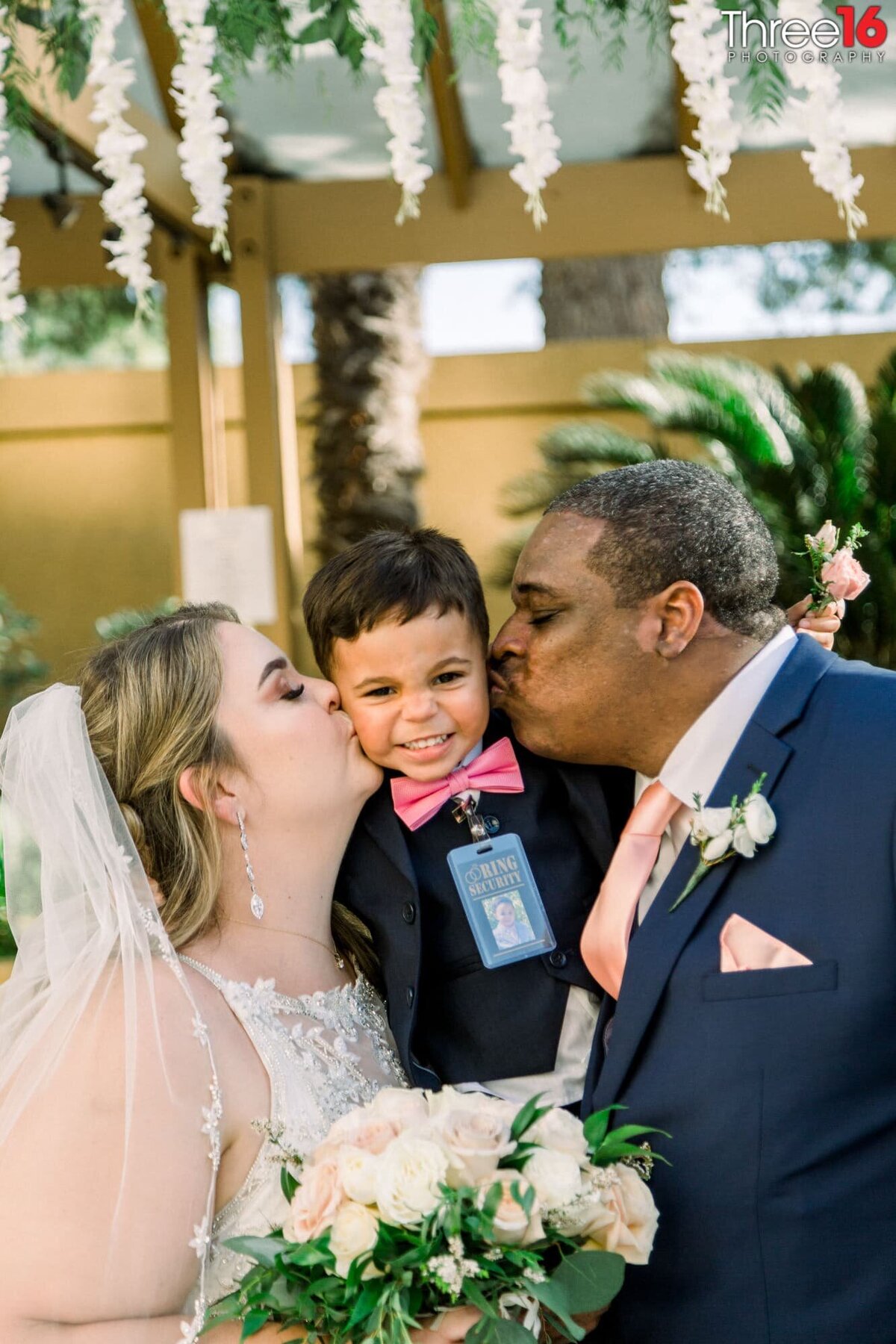 Newly married couple kiss their son on the cheeks