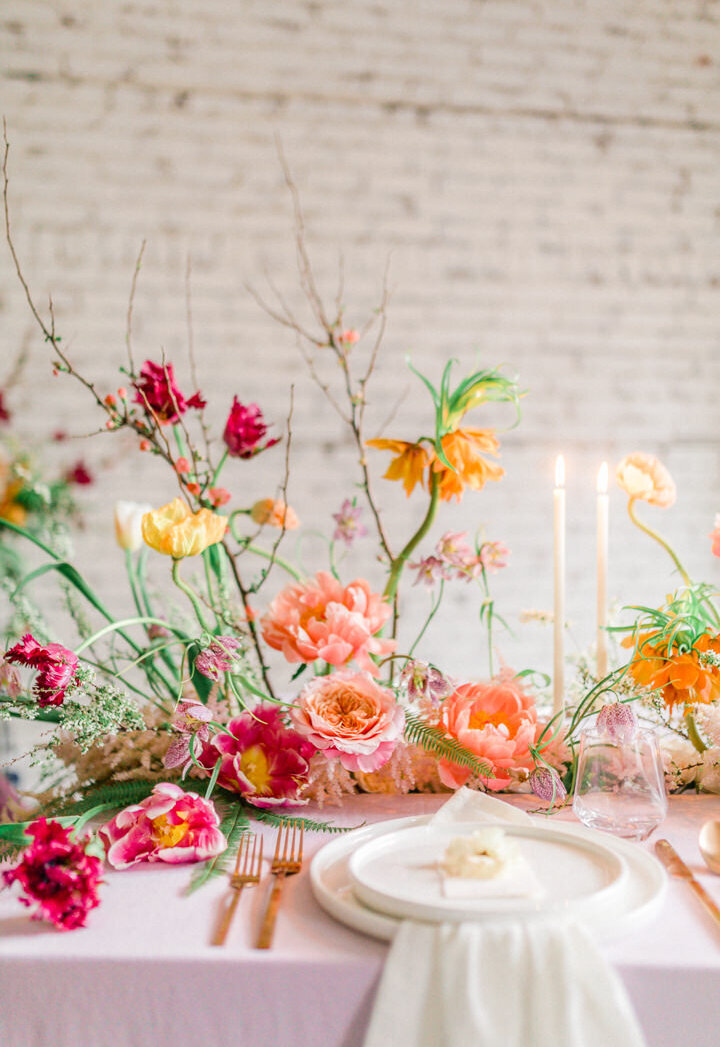 An airy, colourful floral centrepiece decorates a table for a wedding at L’Eloi.