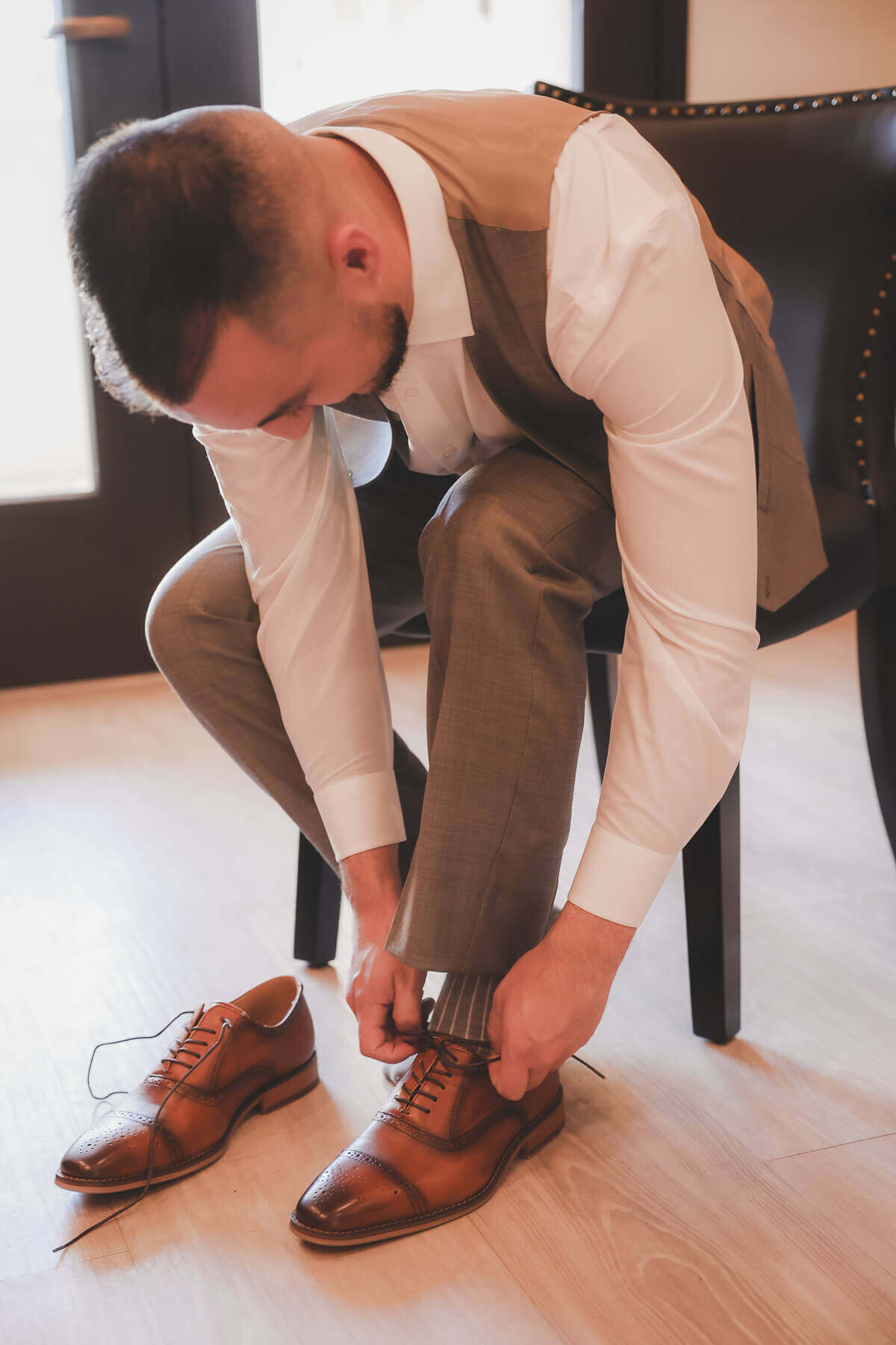 A groom puts on his shoes as he gets ready for his wedding day.