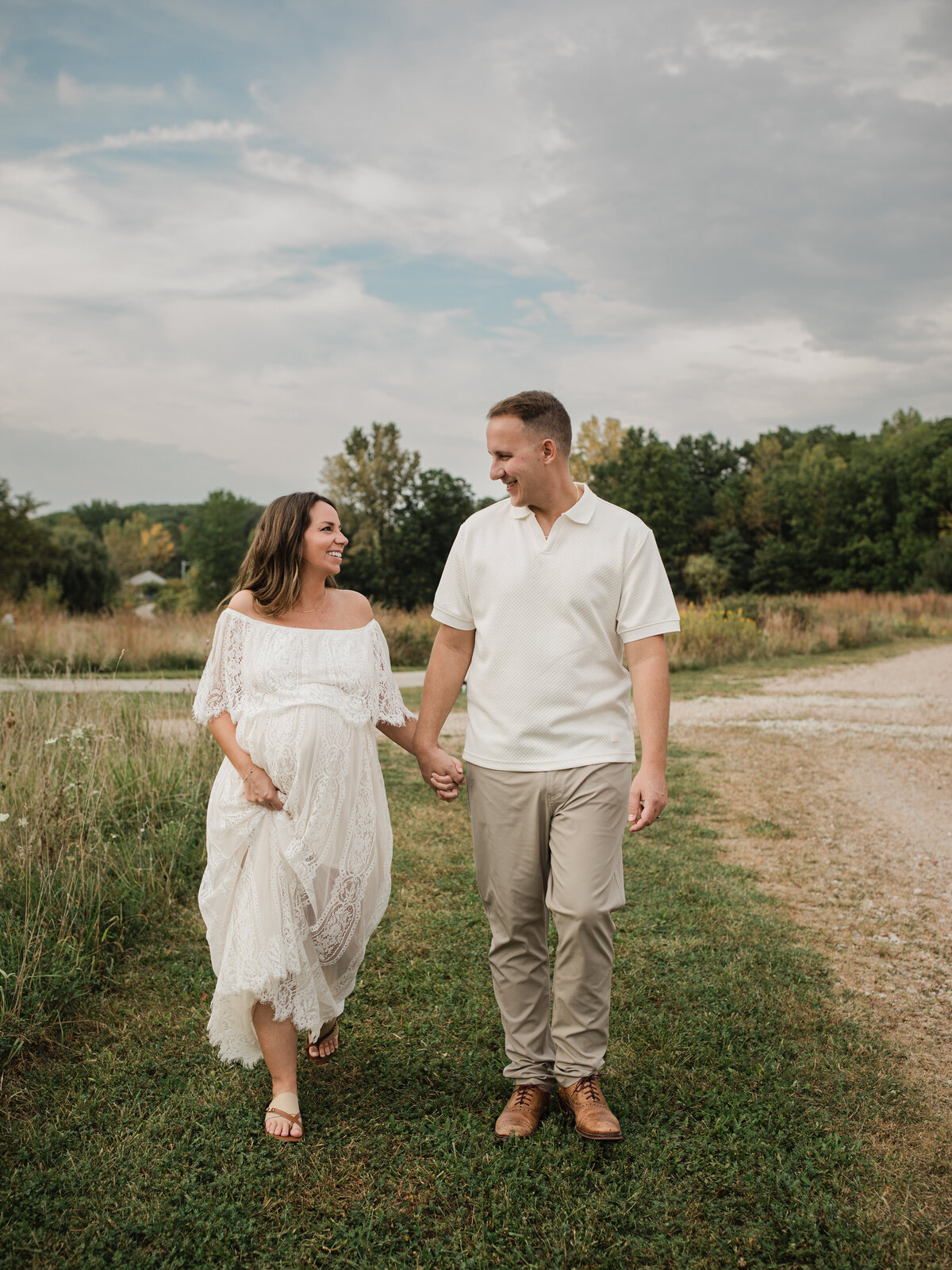 husband and pregnant wife holding hands and walking in park for maternity photoshoot cleveland maternity photographer