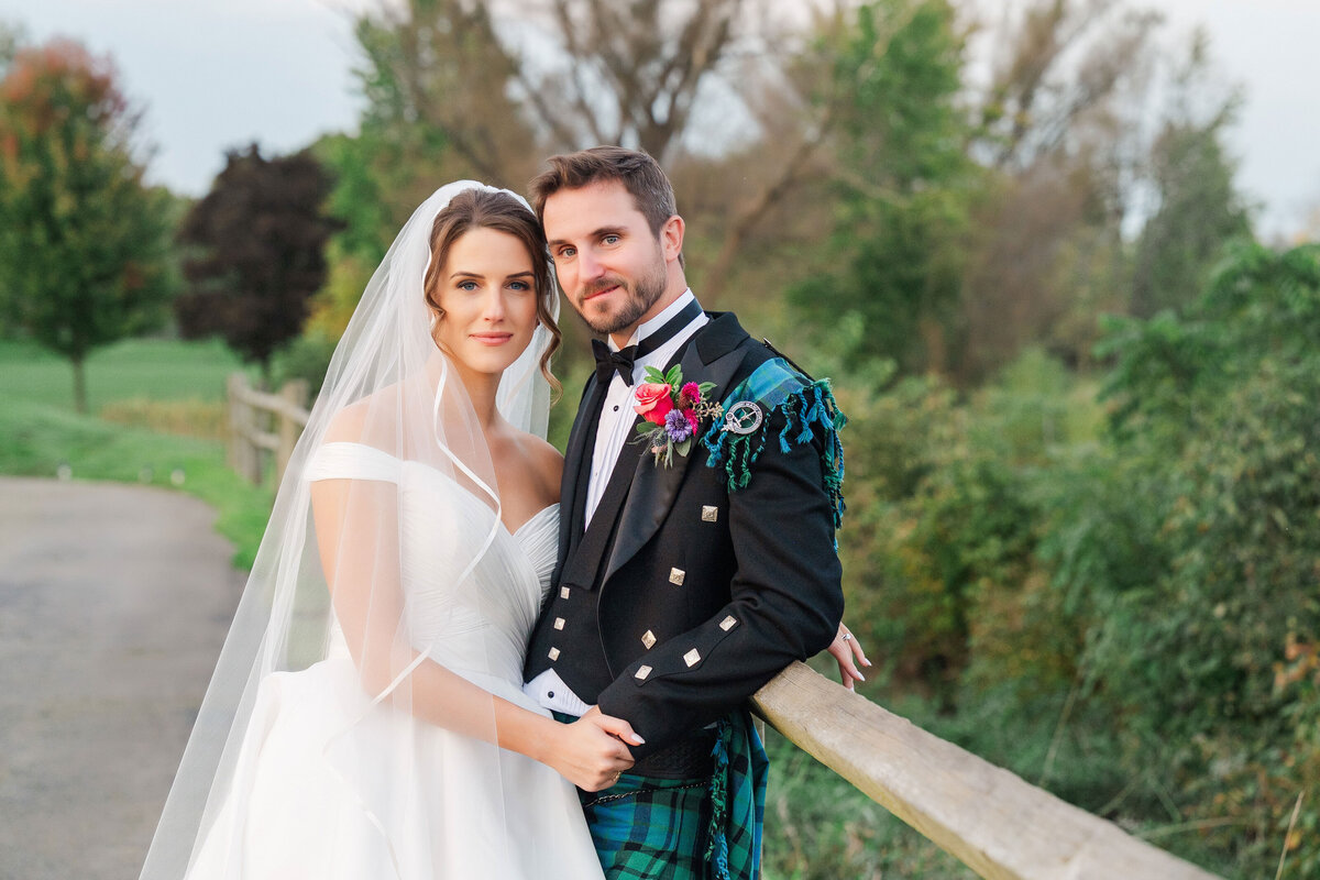 married couple posing on the golf course in wedding dress and formal kilt 