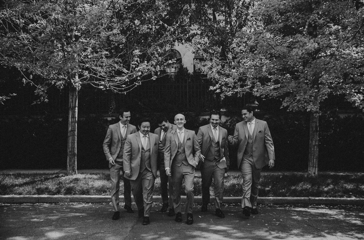 black and white groomsmen walk in street