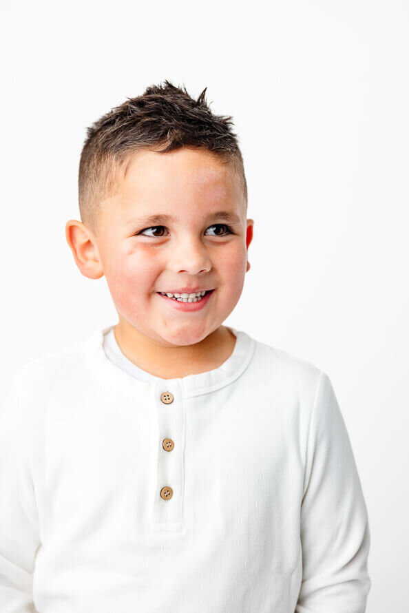 Boy looks at mom off camera during his milestone photo session.