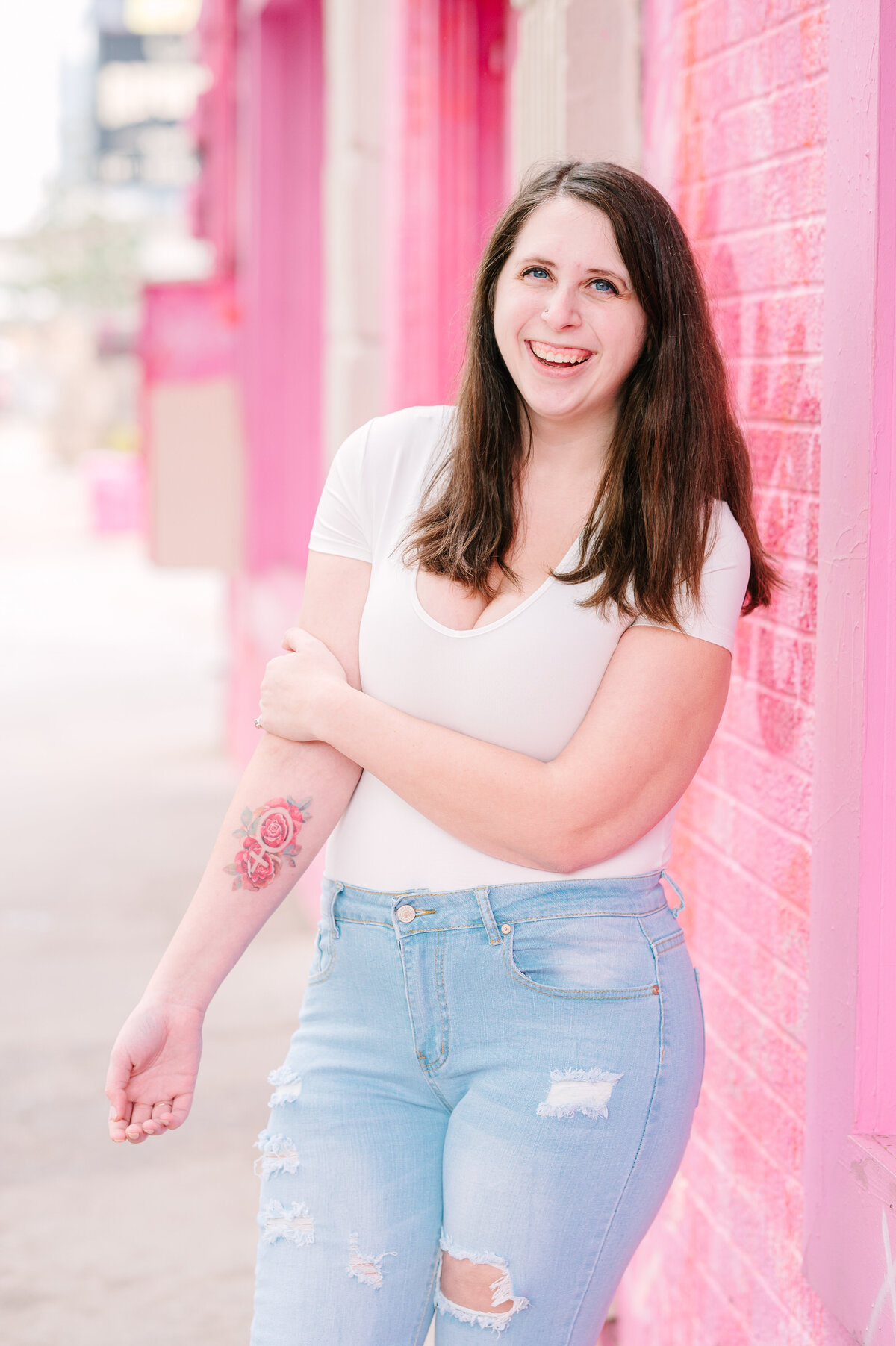 Cait Potter smiling in front of a pink brick wall