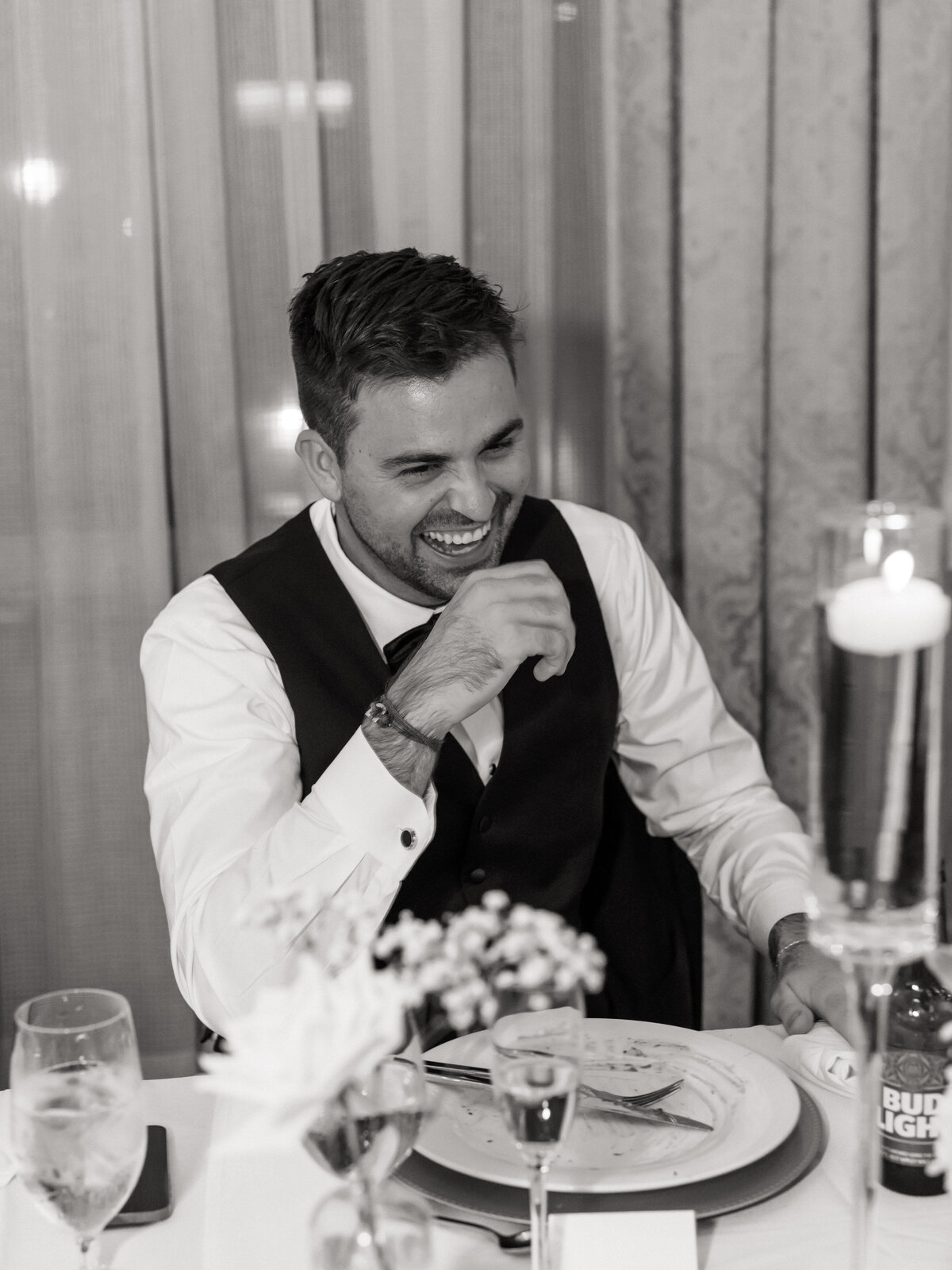 Groomsman laughs during wedding speech at reception, heartfelt candid by a Philadelphia wedding photographer.