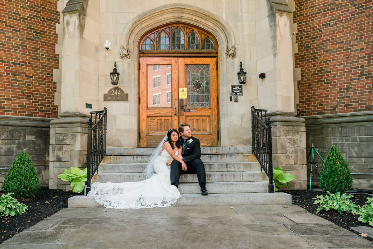 Portrait of the Bride and Groom sitting together on the steps of the Hamilton YMCA.