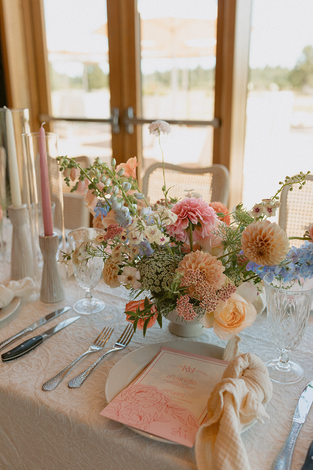 Calligraphy wedding menu resting on a wedding tablesetting plate featuring florals and fine china representing full service design and calligraphy by Life in Letters.