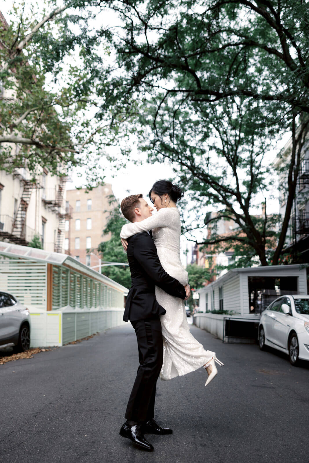 The groom is lovingly carrying the bride in the middle of a street in West Village, NYC. Image by Jenny Fu Studio