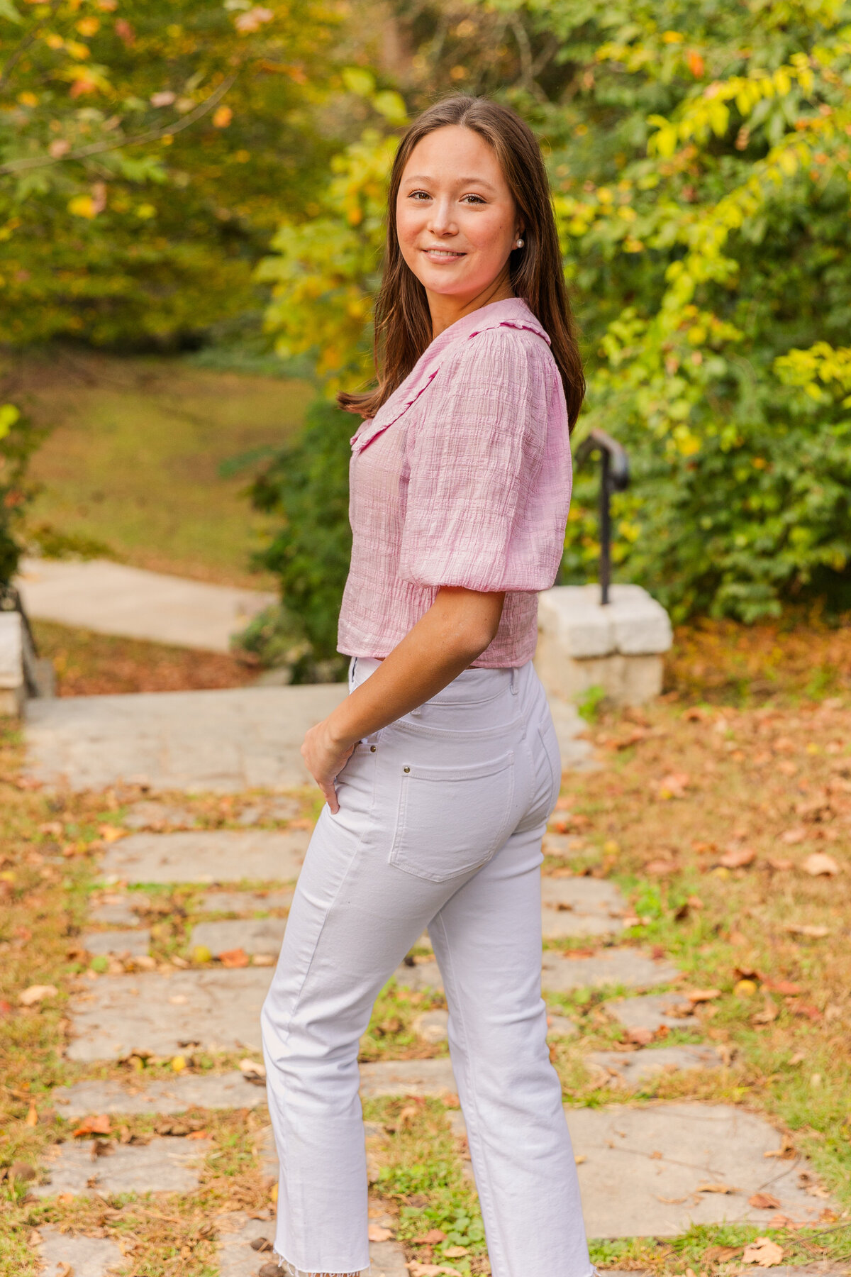 senior girl looking over her shoulder at the camera during photo session on an Atlanta park path