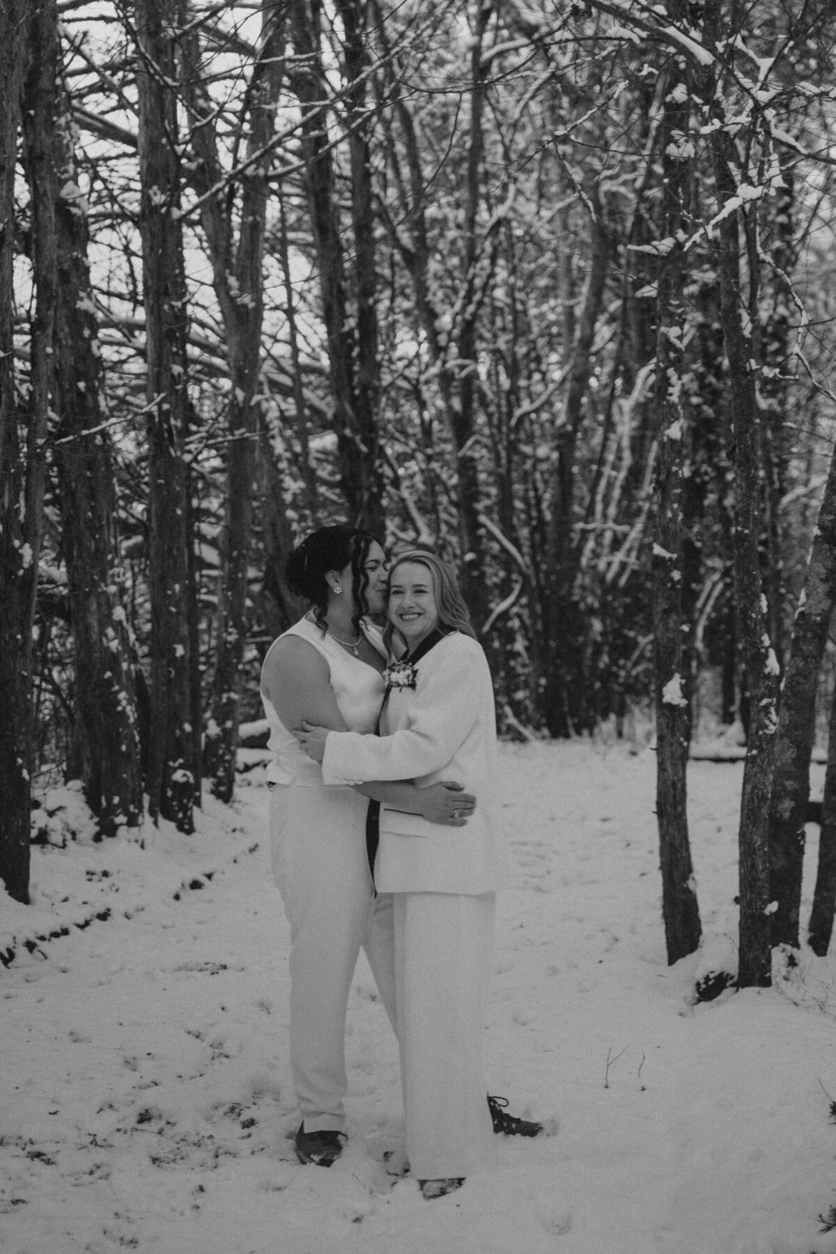 Women embrace in a snowy area on their elopement day 