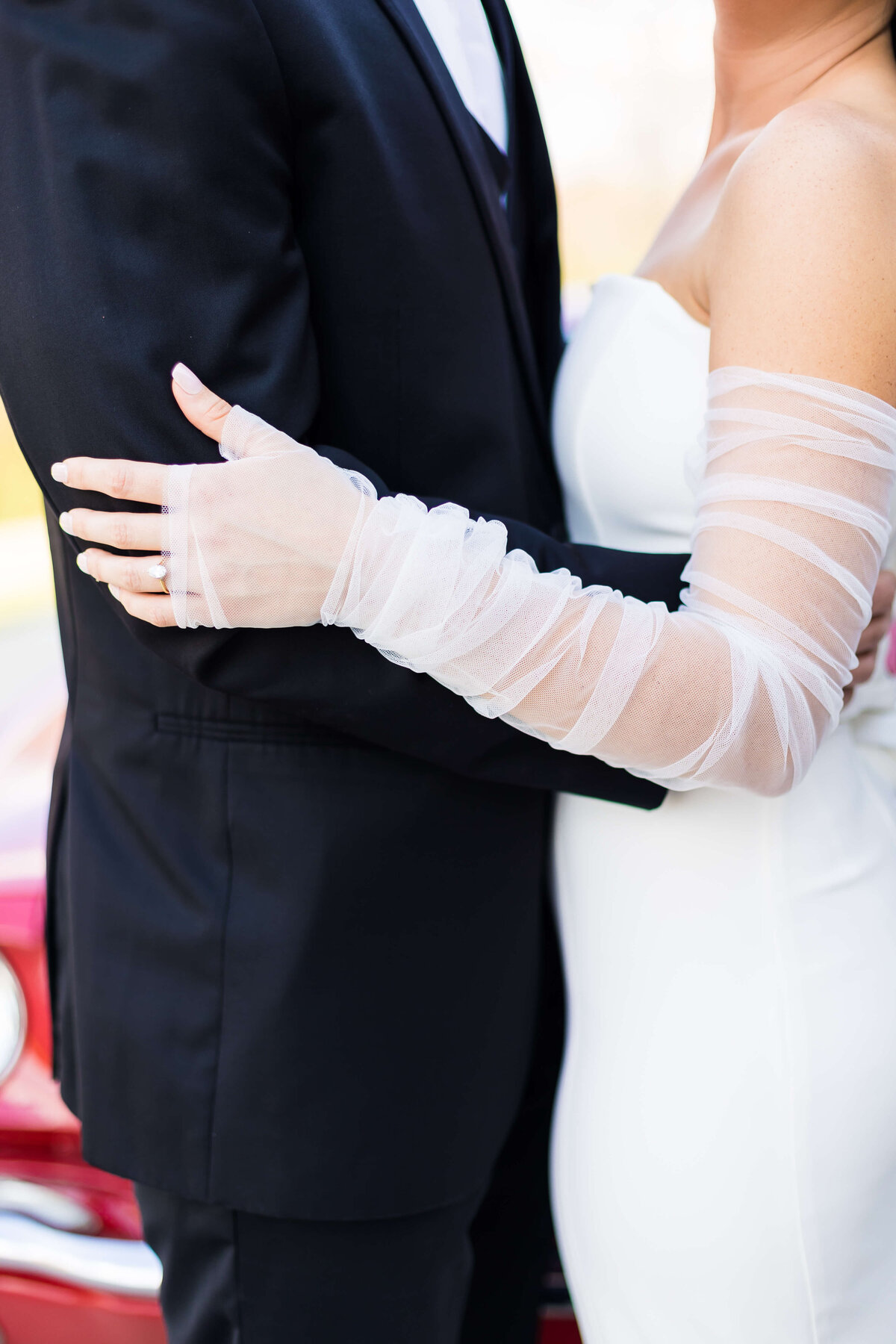 Bride wearing lace sleeves in an embrace with groom