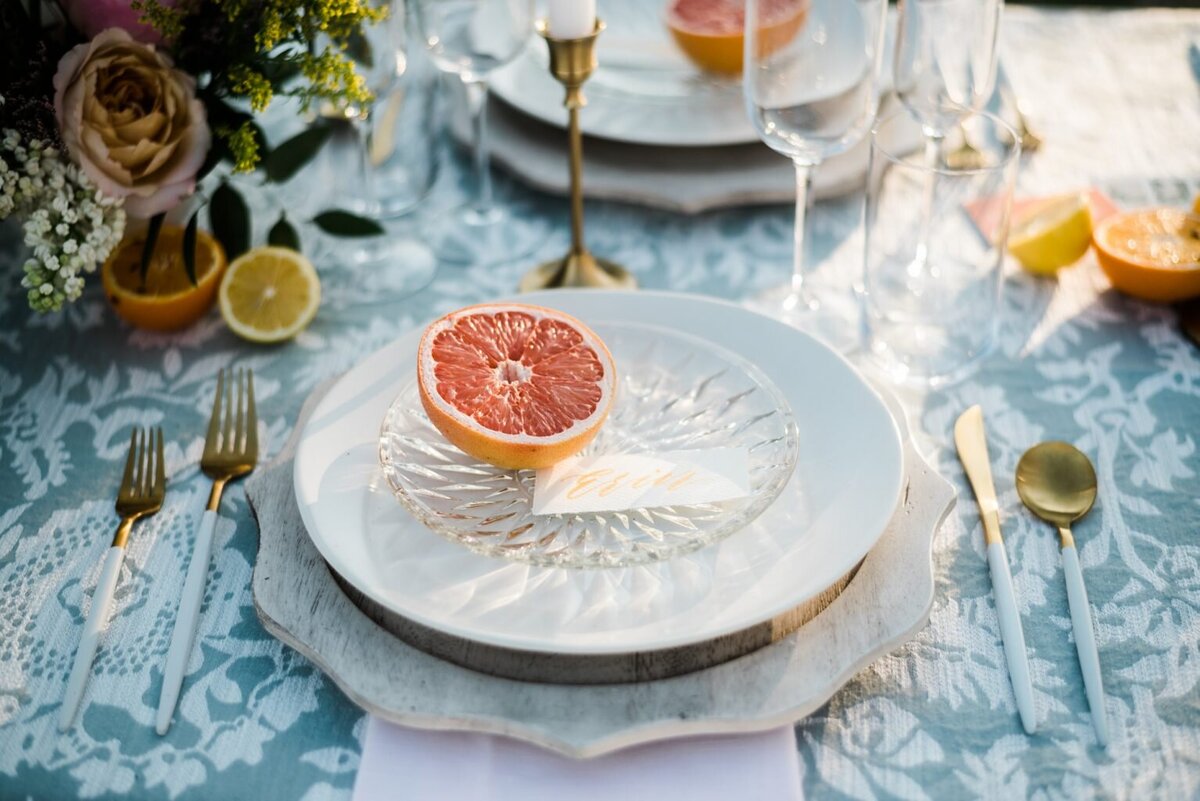 wedding plate detail with calligraphy name card place setting and half a grapefruit as decoration
