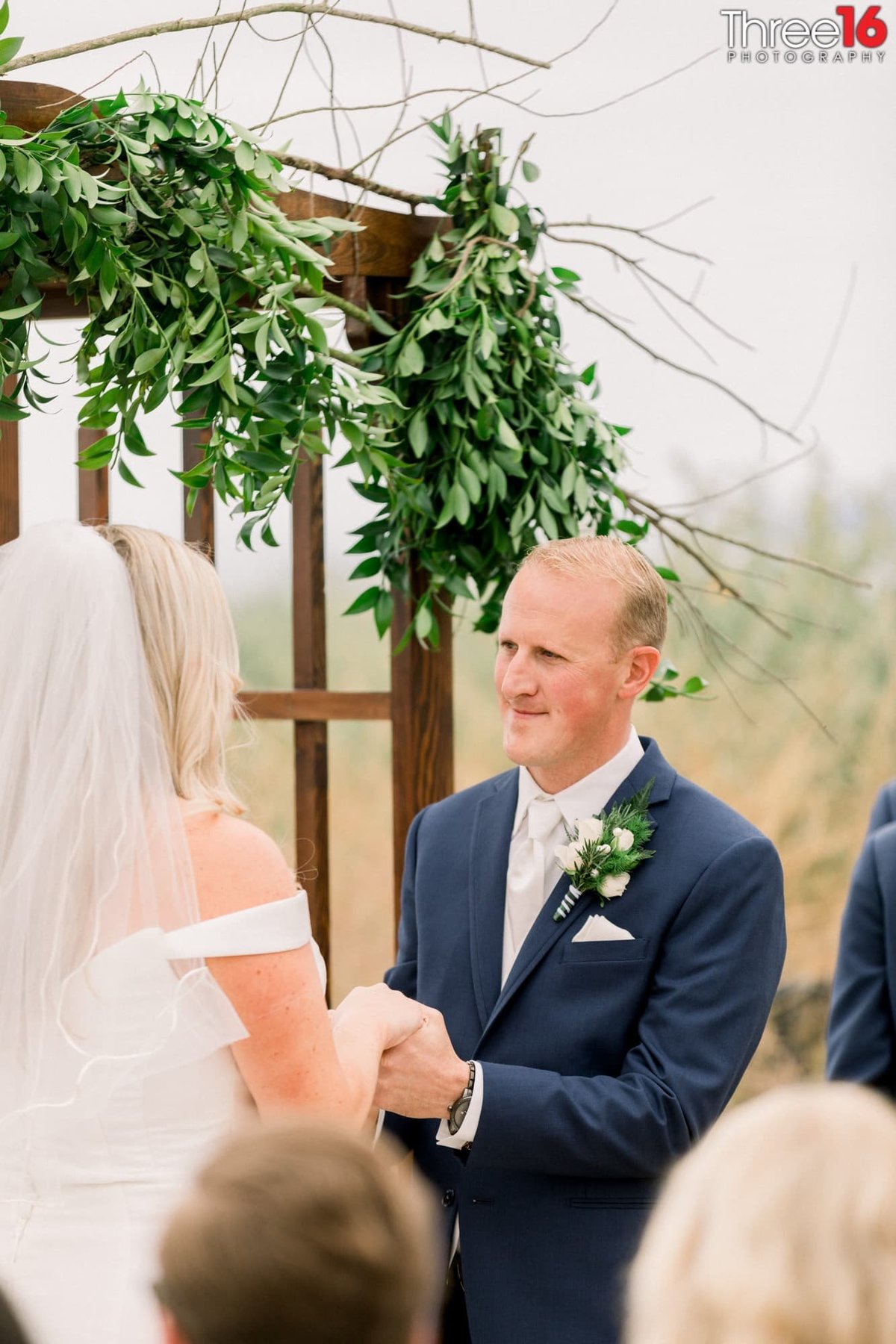 Groom looks at his Bride while holding her hands during the wedding ceremony