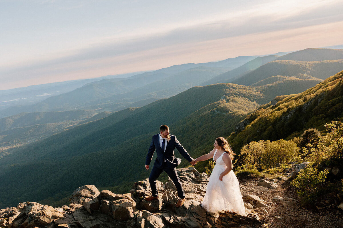 A couple standing atop Stony Man in Virginia at sunrise during their elopement