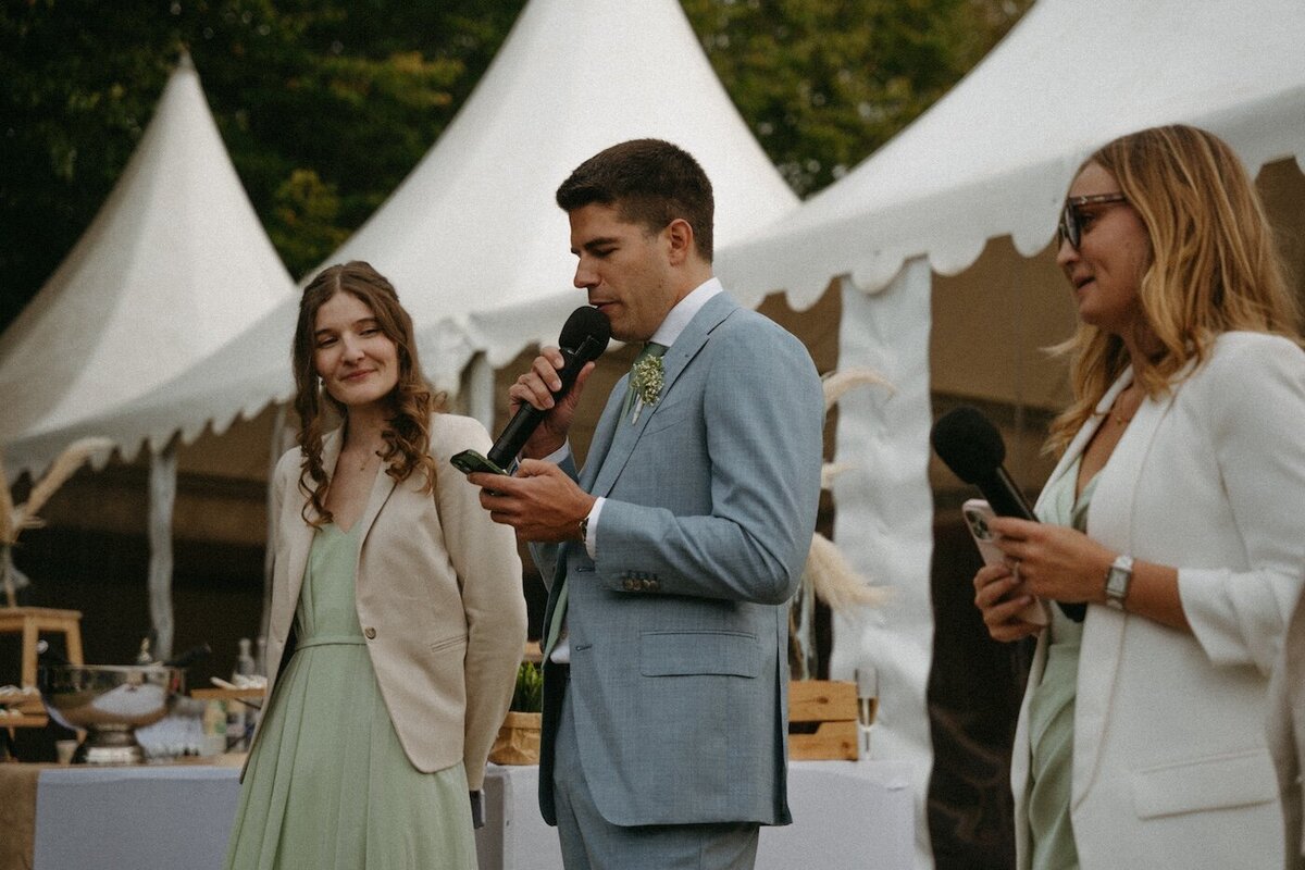 Discours émouvant prononcé devant un chapiteau au Château de Beaussais. Scène capturée par Kamescop, photo et vidéo de mariage en Bretagne.