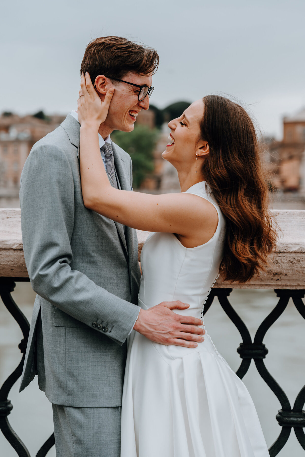 Couple smiling and holding each other on Roman bridge.
