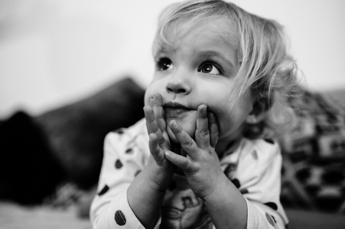 Close up of little girl with head in her hands during family photoshoot