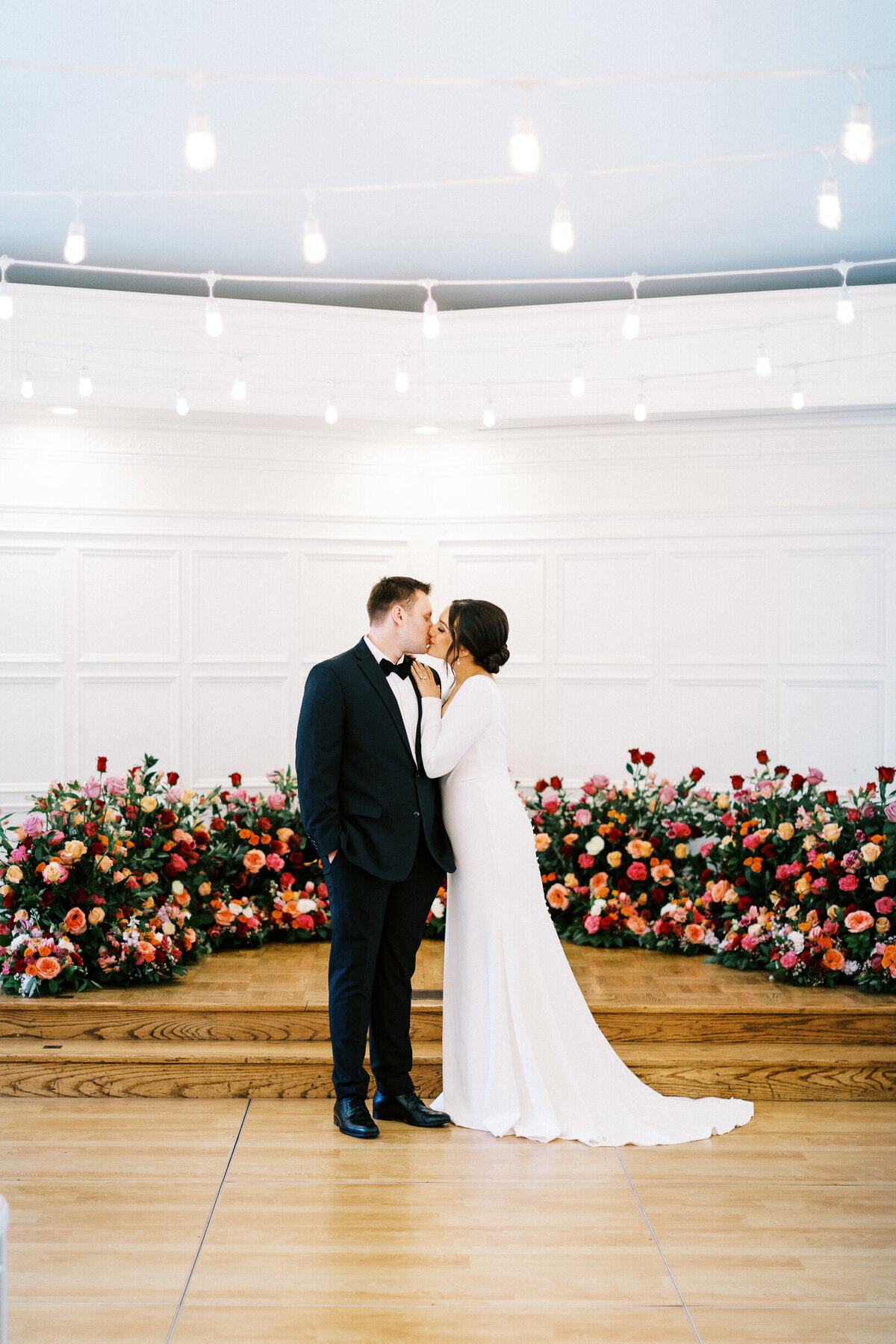 Bride and Groom kissing surrounded with beautiful roses at the ceremony stage.