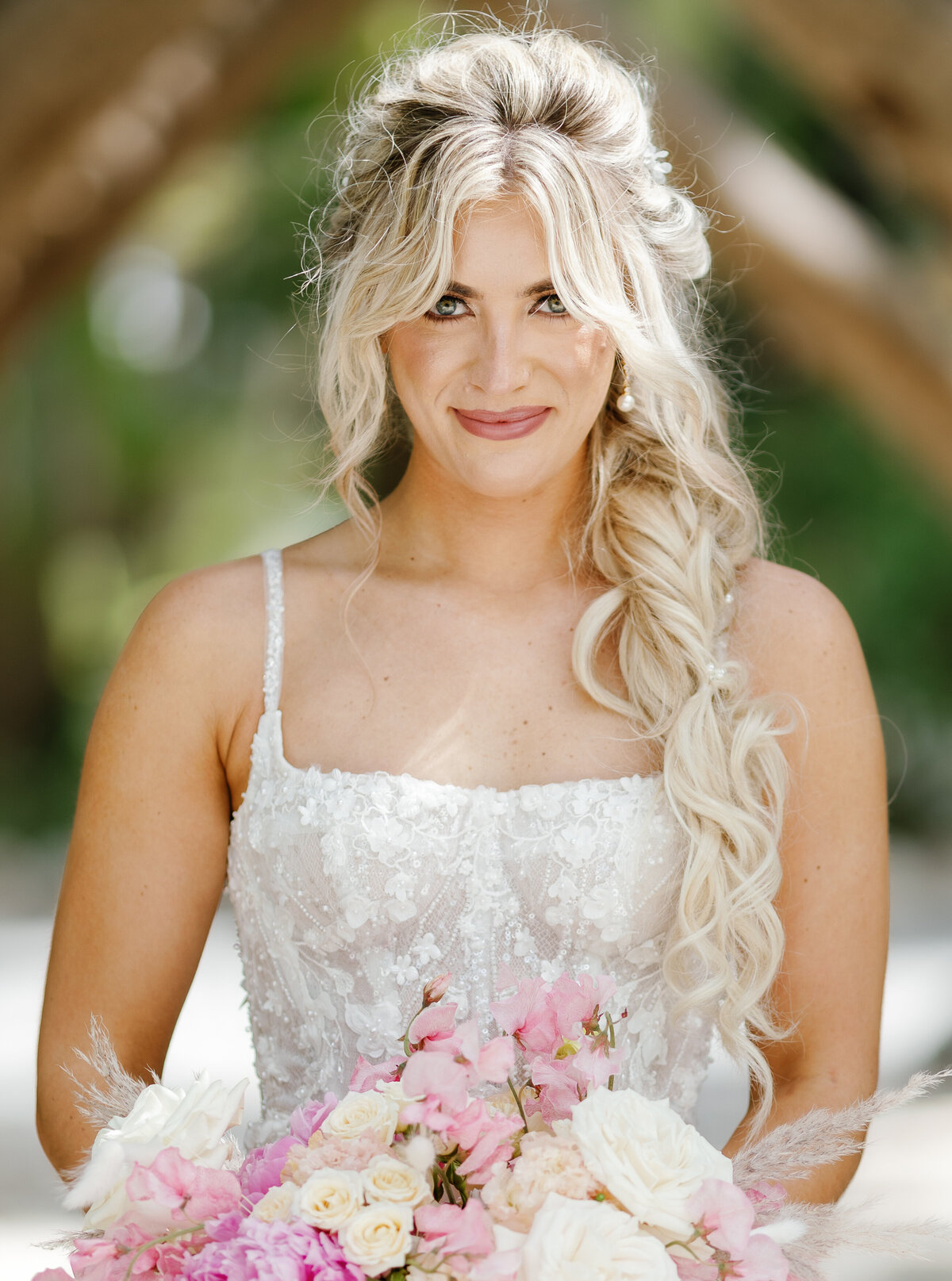 Close-up portrait of a smiling bride holding a bouquet of pink and white flowers, taken by Claudia Amalia Photography in Miami, Florida.