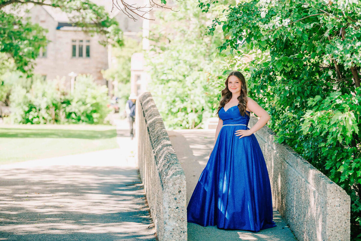 Concrete ramp lined with trees. Girl in a blue dress standing on it. 