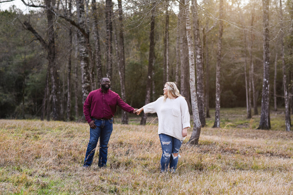 Beautiful Mississippi Engagement Photography: future bride walks and looks back at groom in a field at sunset