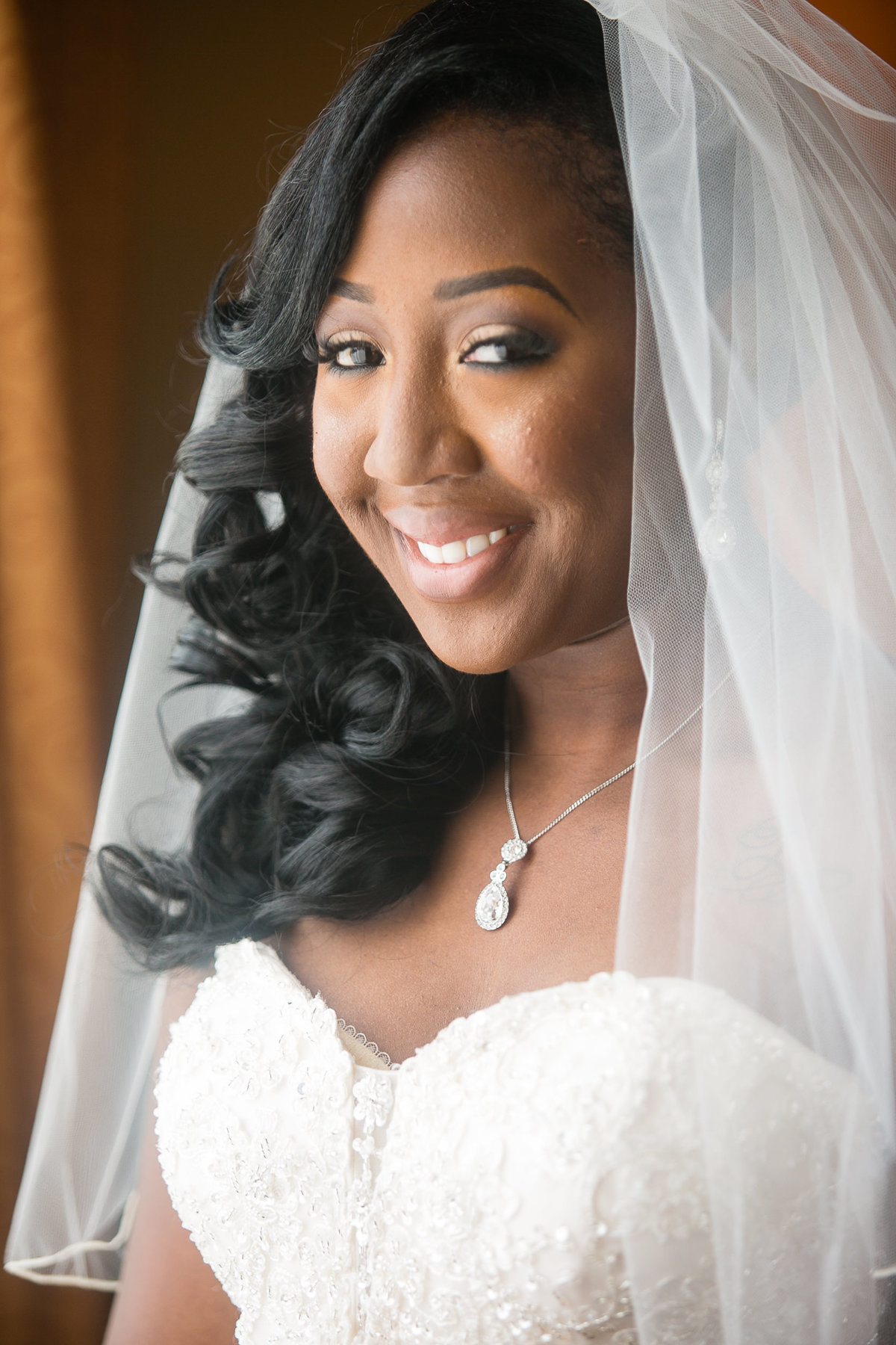 Close up window lit photograph of a smiling bride, just before her wedding ceremony at the Foundry Art Centre.