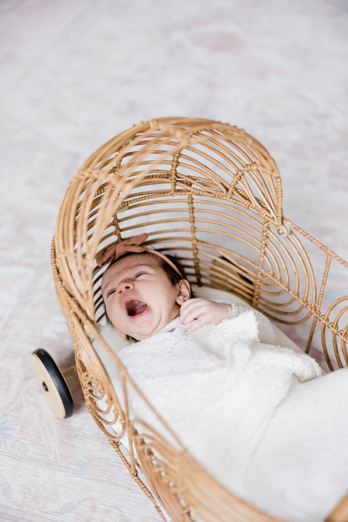 baby yawning in wicker doll bed