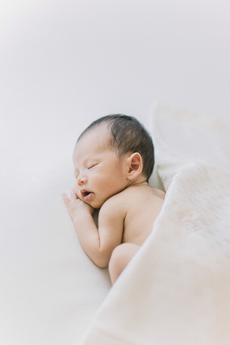 Newborn baby sleeping on his side with pure white kimono for styling. Shot in Yokohama by newborn photographer Yukika Ishikawa Photography, serving Tokyo Japan
