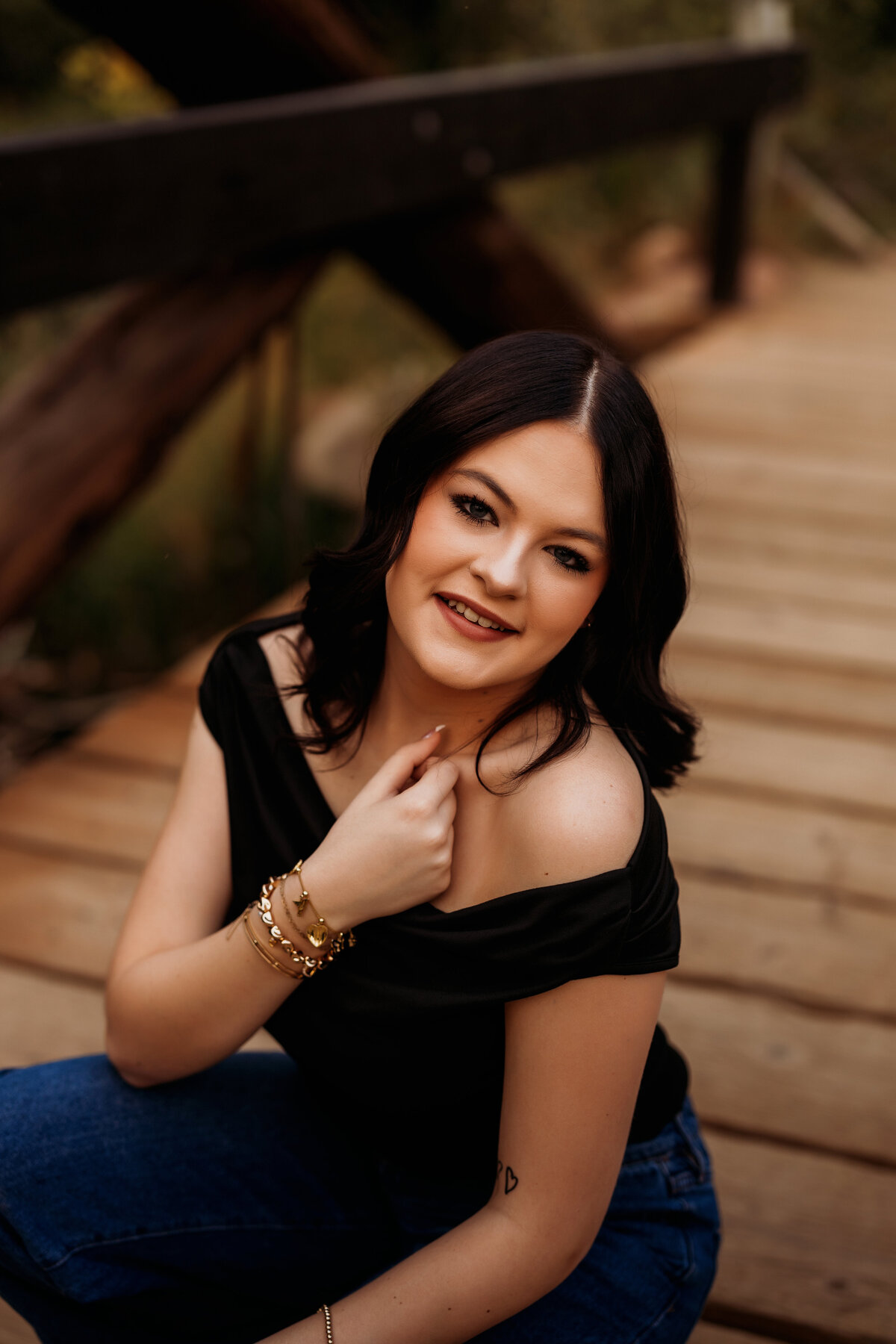 high school senior girl poses on a large wooden bridge just outside of Denver for senior photos