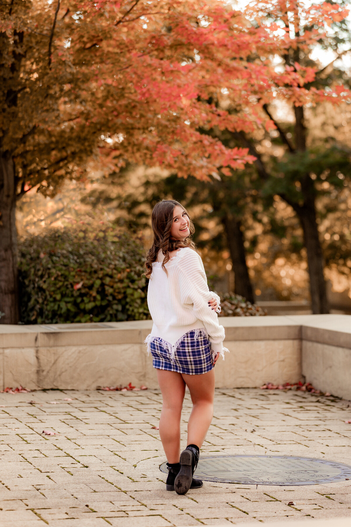 A girl in a plaid skirt playfully looks over her shoulder.