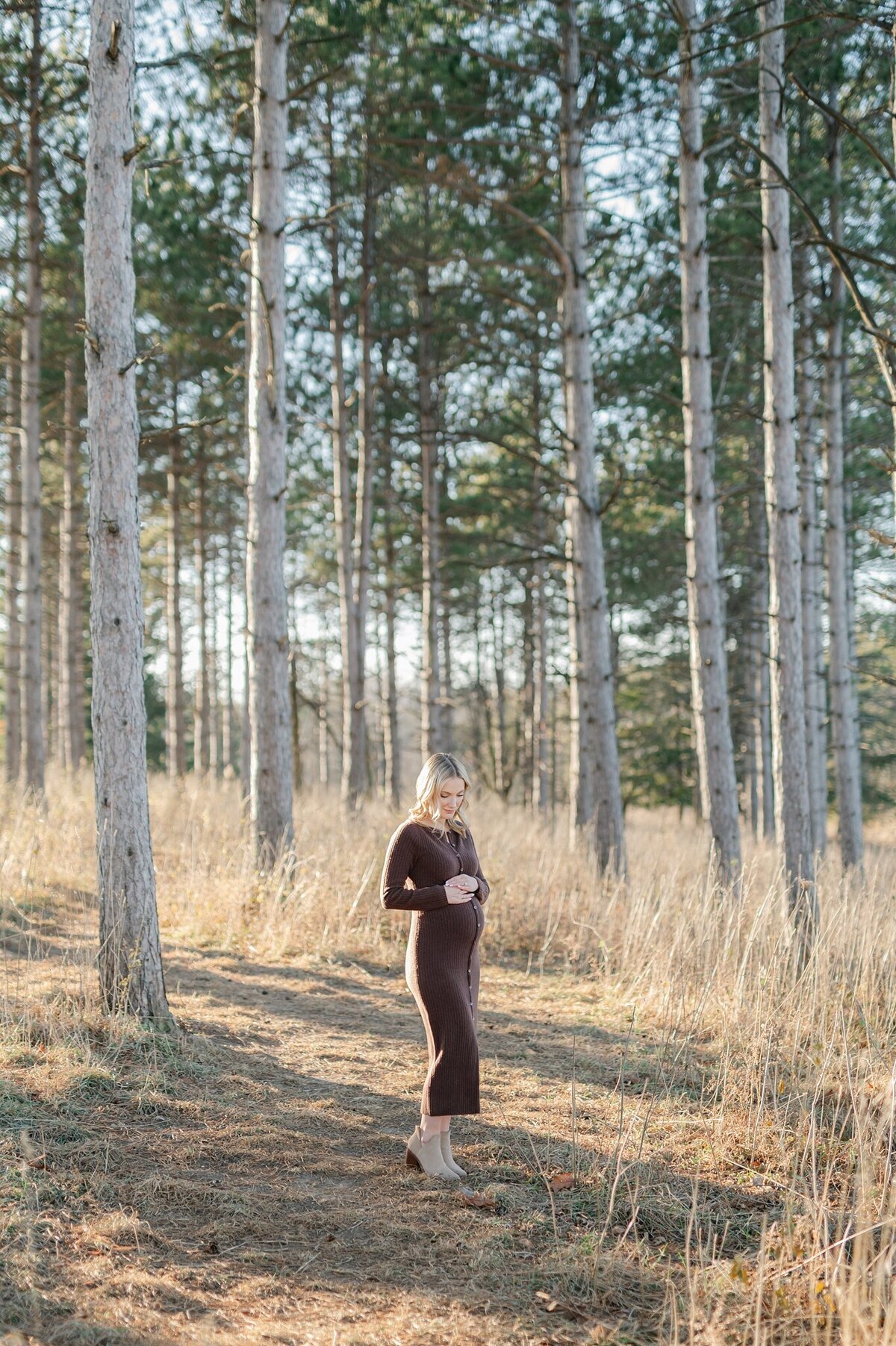 Mom looking down at her belly at Retzer Nature Center  during maternity session in Waukesha, Wisconsin