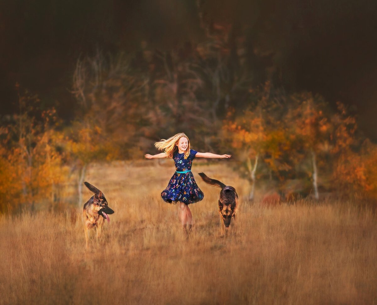 Photo of beautiful girl dancing in the Vedauwoo mountains with her German Shepherd dogs in Autumn.