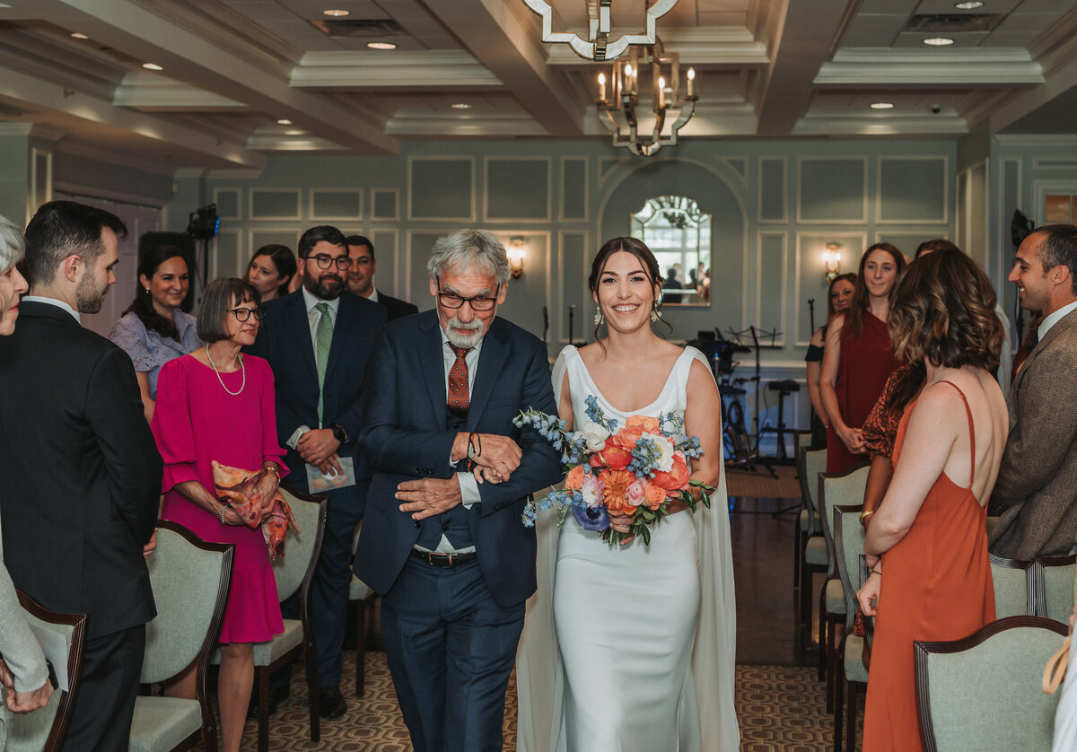 Bride walks up the aisle with her father during an indoor ceremony at Willow Oaks Country Club in Richmond, Virginia.
