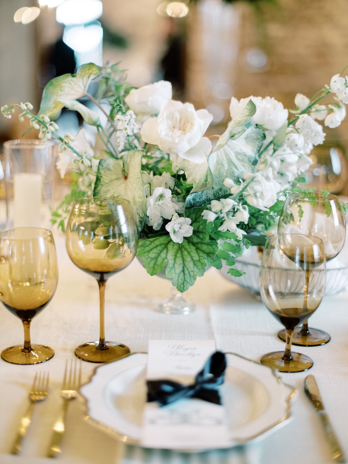 A beautifully arranged centerpiece featuring white flowers and lush greenery, ideal for weddings or elegant gatherings, providing a luxurious and sophisticated atmosphere.