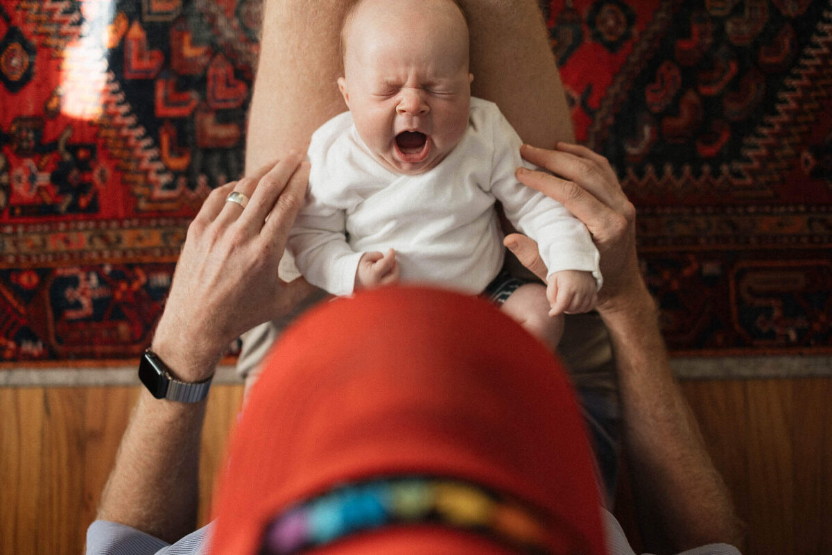 A candid moment of a yawning baby cradled by dad. Capturing authentic Cleveland lifestyle newborn photography.