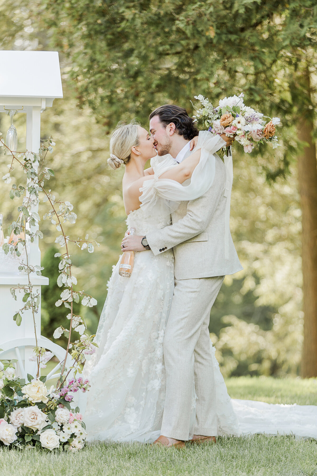 A bride and groom share a kiss at their wedding reception Her bouquet is draped over her groom's neck. Captured by top new england wedding photographer lia rose weddings.