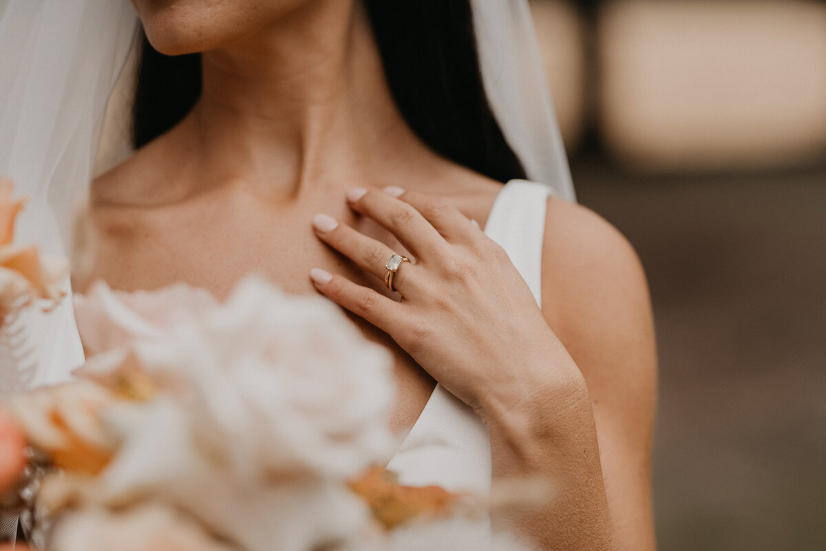 Bridal photo inspiration, bride holding gorgeous peach bouquet, showcasing stunning wedding ring, captured by Ash Maclean Photography, romantic elopement and wedding photographer in Red Deer, Alberta. Featured on the Bronte Bride Vendor Guide.