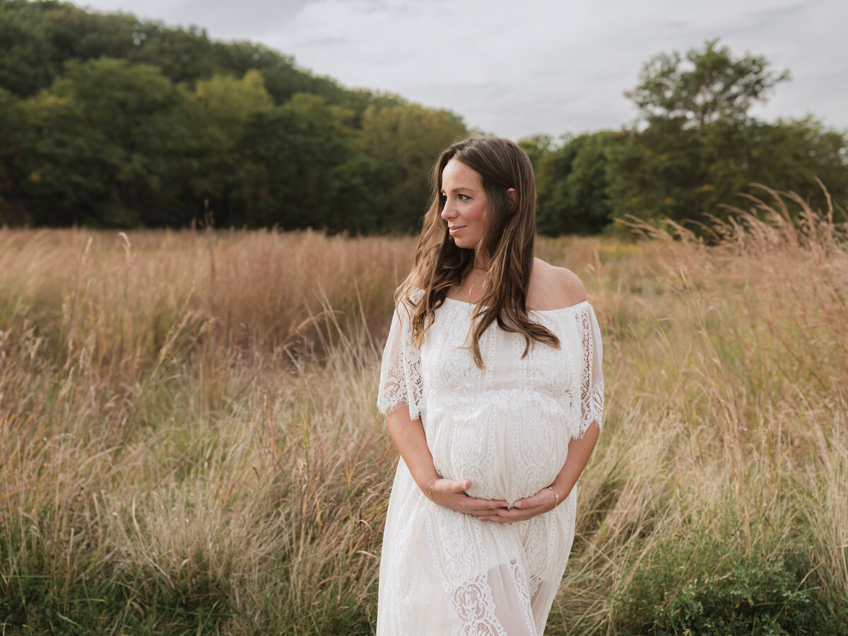 pregnant mother in white lace maternity gown holding baby bump for maternity photoshoot cleveland maternity photographer
