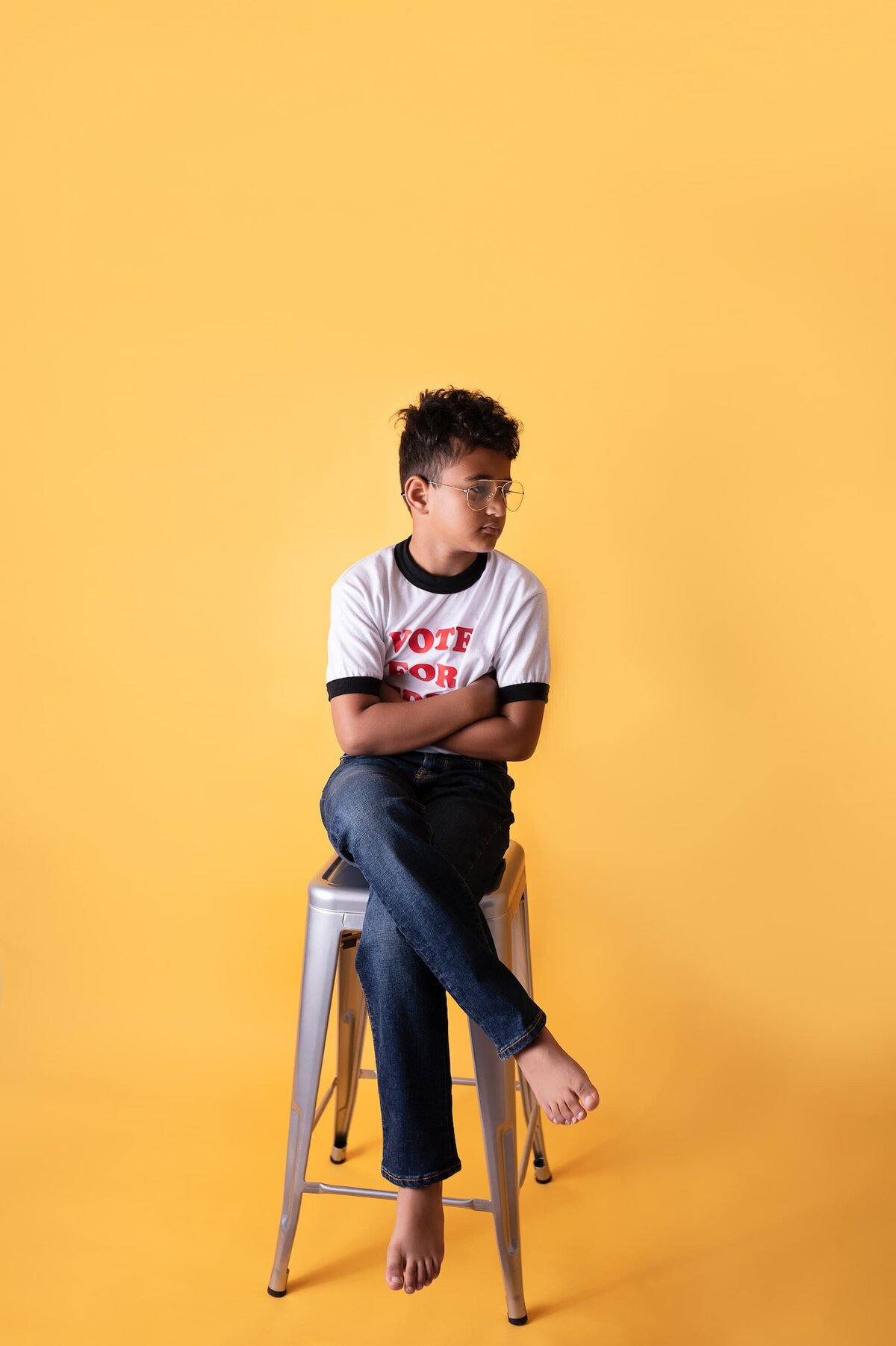 boy wearing vote for pedro shirt sitting on a stool with a yellow backdrop