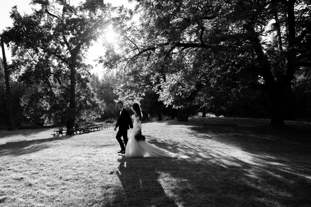 bride and groom walking along under the shadows of the trees
