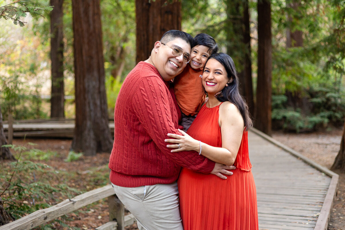 Happy family portrait with a pregnant mother, father, and son on a wooden forest path – Ellobelle Photography