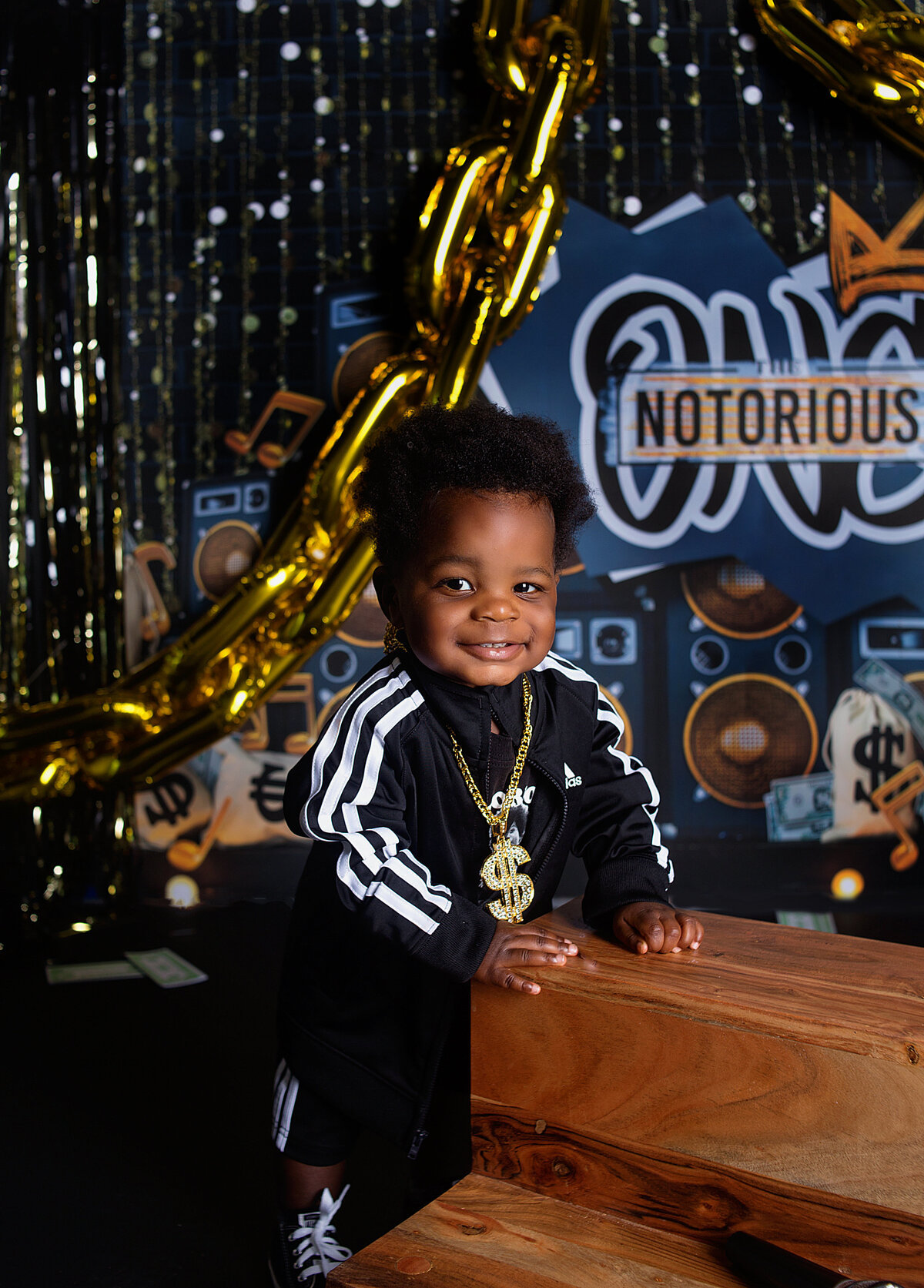 Baby boy wearing gold chain and jacket during first birthday cake smash photoshoot with Franklin, Tennessee Family photographer