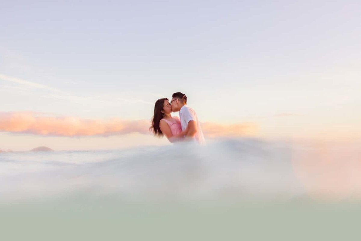 Couple in the ocean embrace and kiss as Love + Water photograph their engagement portraits at the beach