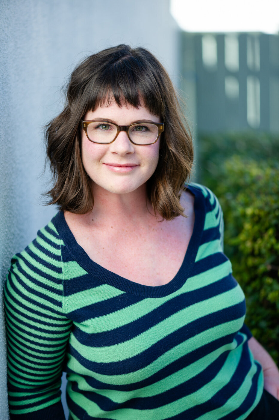 Commercial Acting Headshot of actress Katie Adams wearing glasses and green striped shirt.