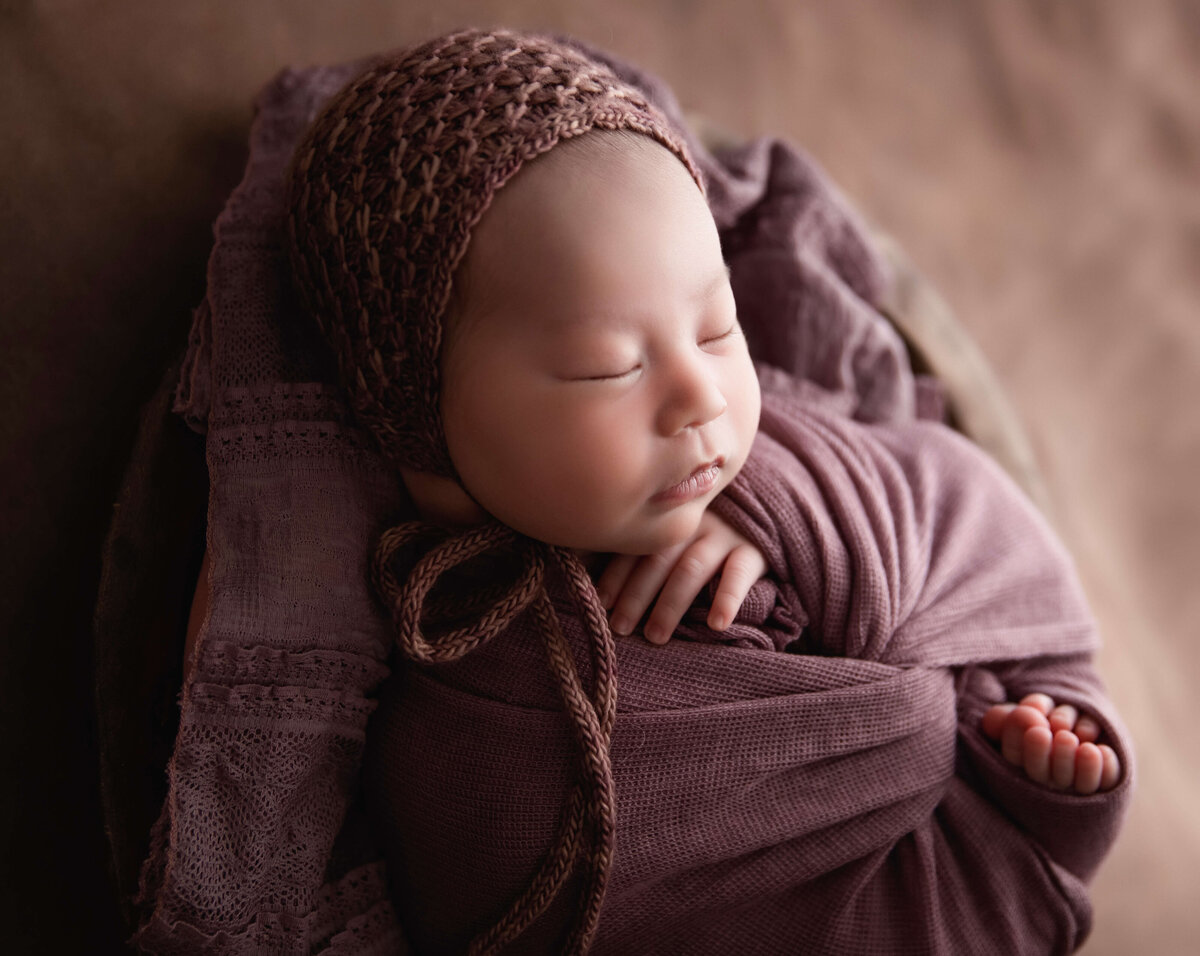 Newborn baby girl in mauve wrapped in an Erie Pa photography studio